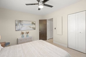 A bedroom with a bed, a ceiling fan, a door, and a painting on the wall. - Sarasota 'Starburst' Home | Heated Pool | Dogs OK (Sarasota)