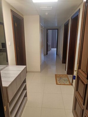 A hallway with wooden doors, a tiled floor, and a small rug. - "Sahwa Residency" our cozy 2-bedroom fully furnished apartments Taqah / Salalah (Taqah)