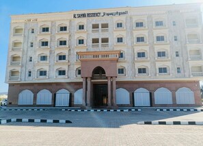 A multi-story building with a central entrance, large windows, and a sign reading "Al-Sahwa Residency." - "Sahwa Residency" our cozy 2-bedroom fully furnished apartments Taqah / Salalah (Taqah)