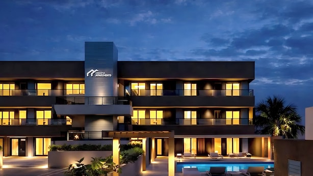 A modern multi-story hotel with a swimming pool and outdoor seating area. - Kibaima Apartments (Oranjestad)