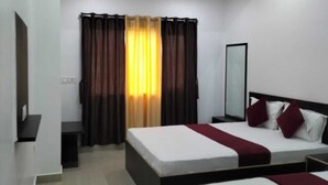 A hotel room with two beds, a ceiling fan, and a large window with curtains. - Hotel Temple View (Gaya)