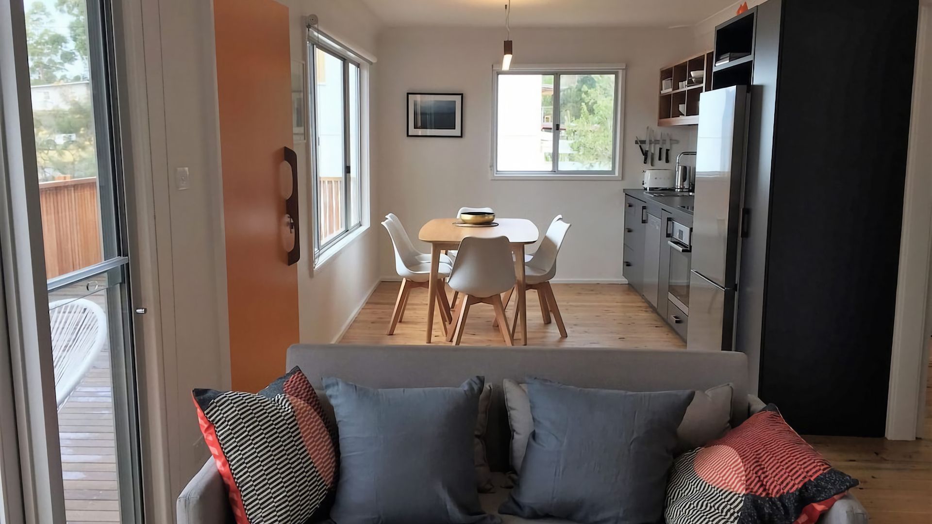 Une cuisine moderne avec un coin repas, un canapé avec des coussins et une vue sur l’extérieur.