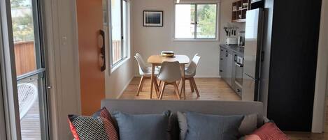 Une cuisine moderne avec un coin repas, un canapé avec des coussins et une vue sur l’extérieur.