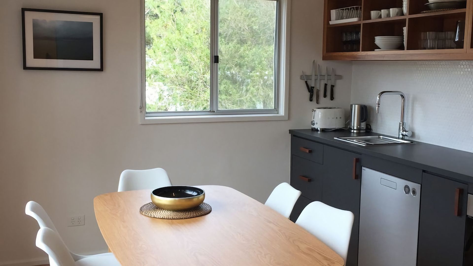 Une cuisine moderne avec une table à manger, des chaises, une fenêtre et un évier.
