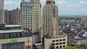 A hotel with a Holiday Inn sign, surrounded by high-rise buildings and a traditional neighborhood. - Jinglai Hotel Shanghai Songjiang  (Shanghai)