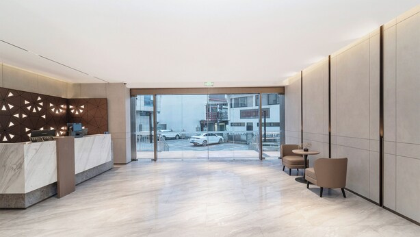 A modern reception area with a marble counter, seating, and a view of the street. - Jinglai Hotel Shanghai Songjiang  (Shanghai)