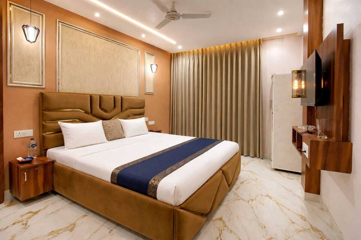 Habitació d'hotel amb un llit gran, un ventilador de sostre, una televisió i un minibàr.