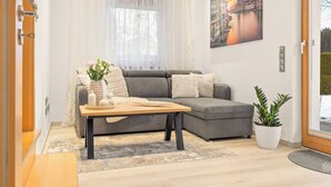 Uma sala de estar moderna com um sofá modular cinza, uma mesa de centro de madeira e uma pintura de paisagem urbana na parede.