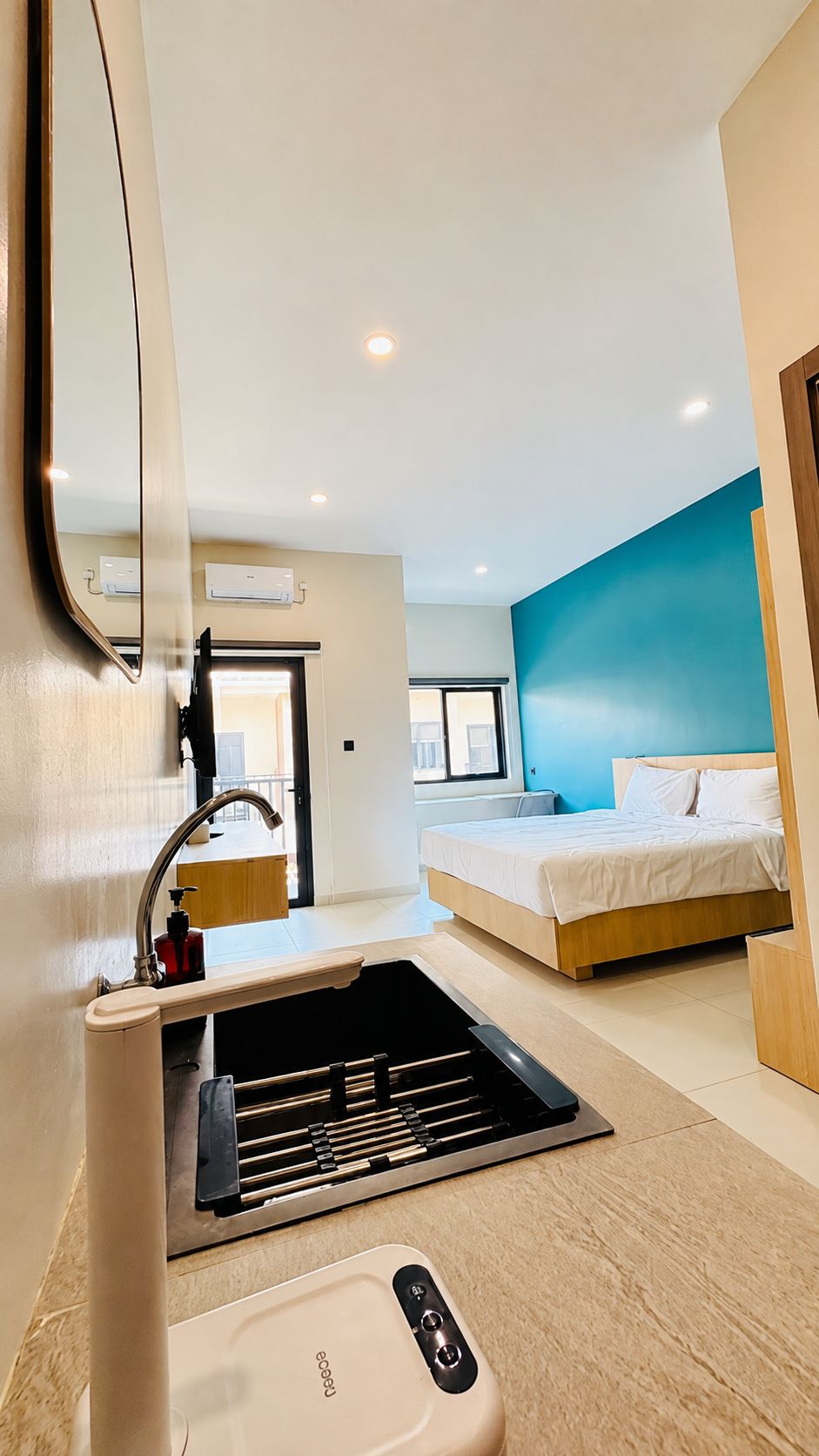 A modern hotel room with a bed, a built-in sink, and a mirror.