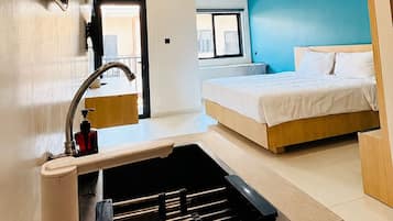 A modern hotel room with a bed, a built-in sink, and a mirror.