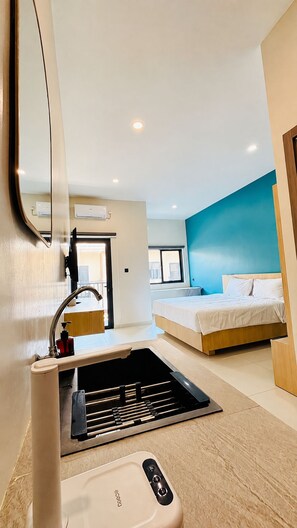 A modern hotel room with a bed, a built-in sink, and a mirror.
