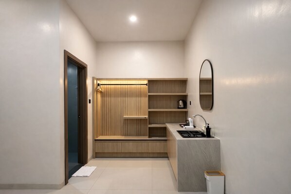A compact kitchenette with a built-in oven, a sink, and a mirror above it. - Bene Residence (Sumbawa Barat)