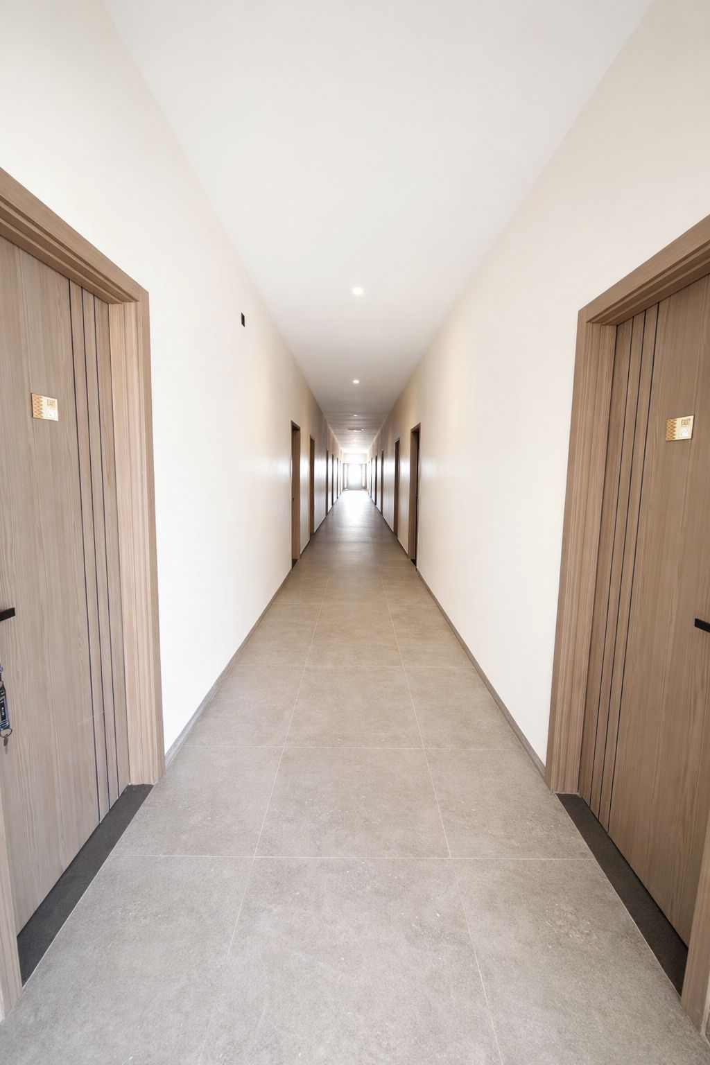 A long, narrow hallway with wooden doors on both sides and a tiled floor.