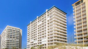 A beachfront hotel with multiple floors, balconies, and a sandy beach in the foreground. - Bluewater 103 (Orange Beach)