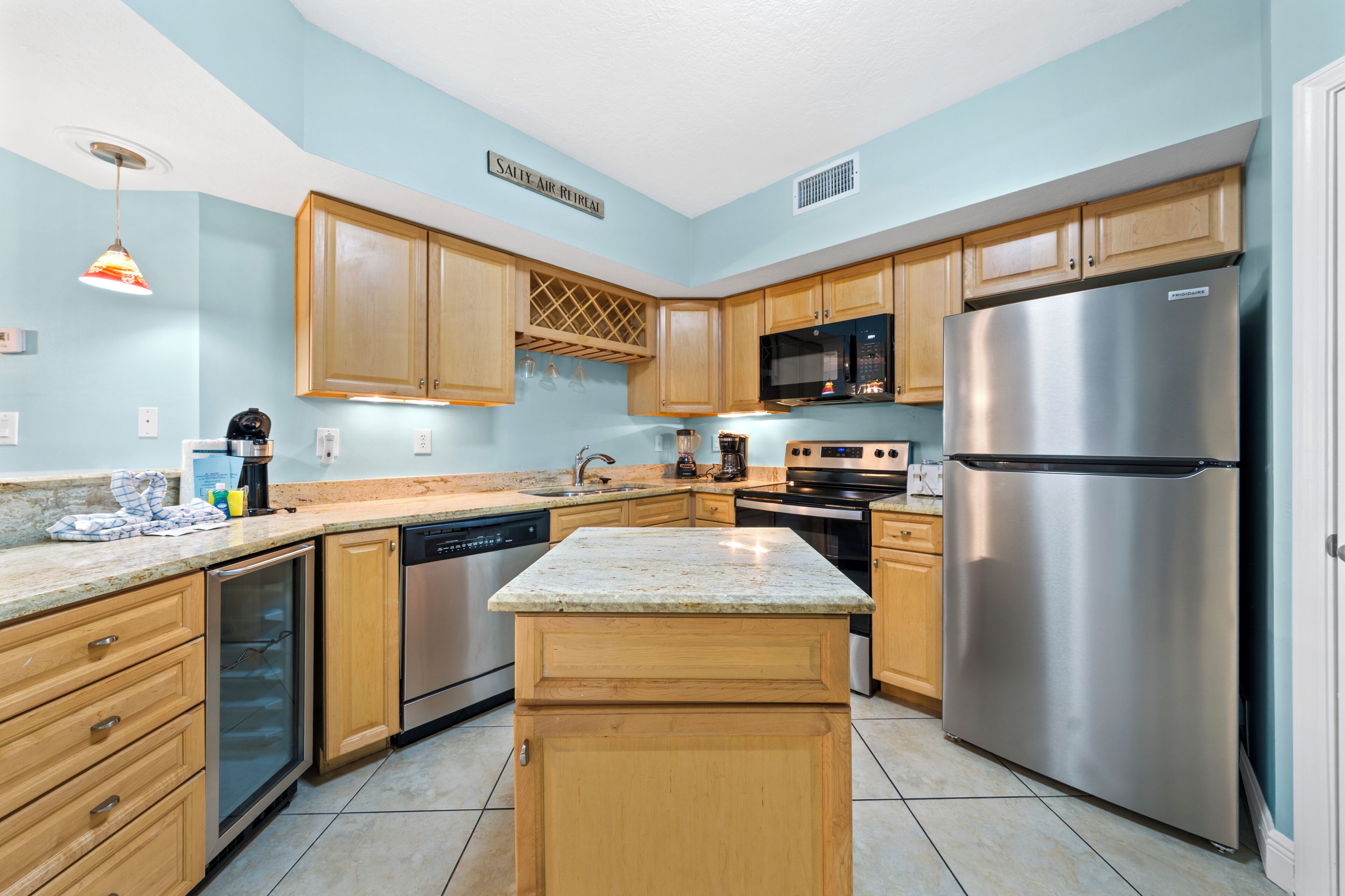 A modern kitchen with wooden cabinets, stainless steel appliances, and a granite countertop.