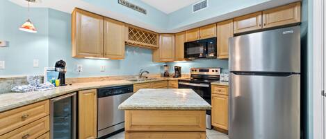 A modern kitchen with wooden cabinets, stainless steel appliances, and a granite countertop.
