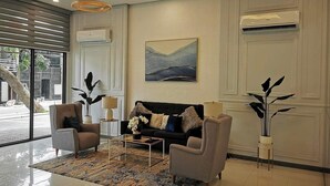 Ein modernes Wohnzimmer mit einer Couch, zwei Sesseln, einem Couchtisch und einem großen Fenster.