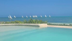 A pool with a view of the ocean and sailboats. - Lost Soles Lodge (Jambiani)