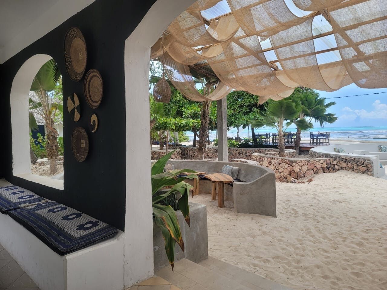 A beachside lounge with a stone wall, outdoor seating, and a view of the ocean.