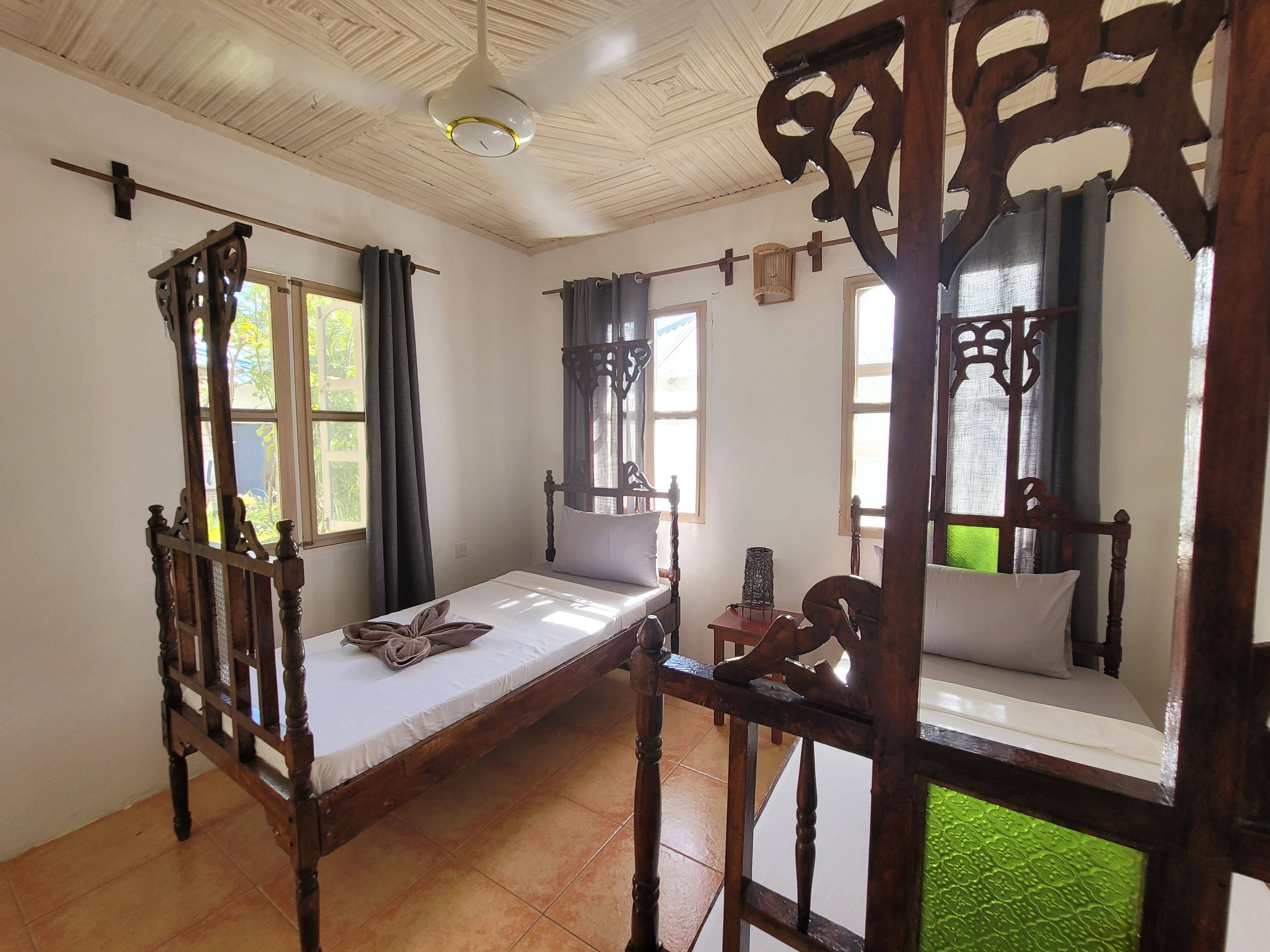 A room with a wooden bed, a small table, and a window with curtains.