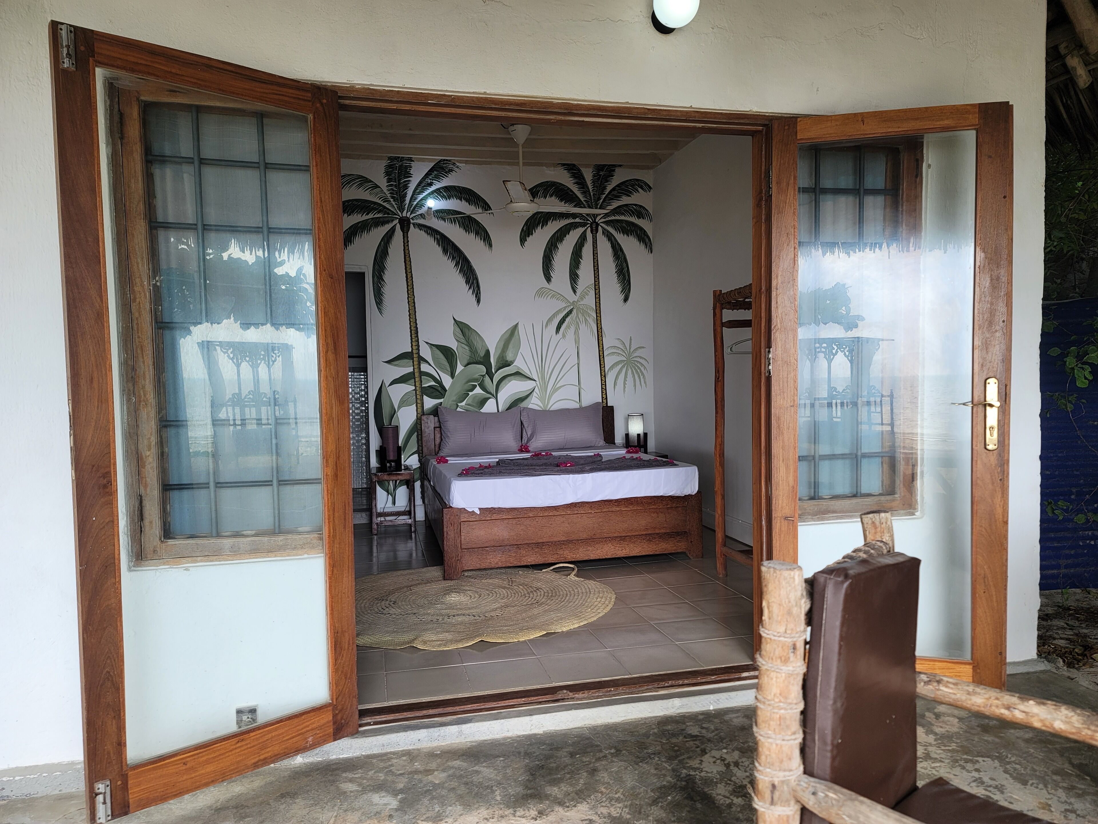 A bedroom with a bed, a wooden door, and a view of a garden.