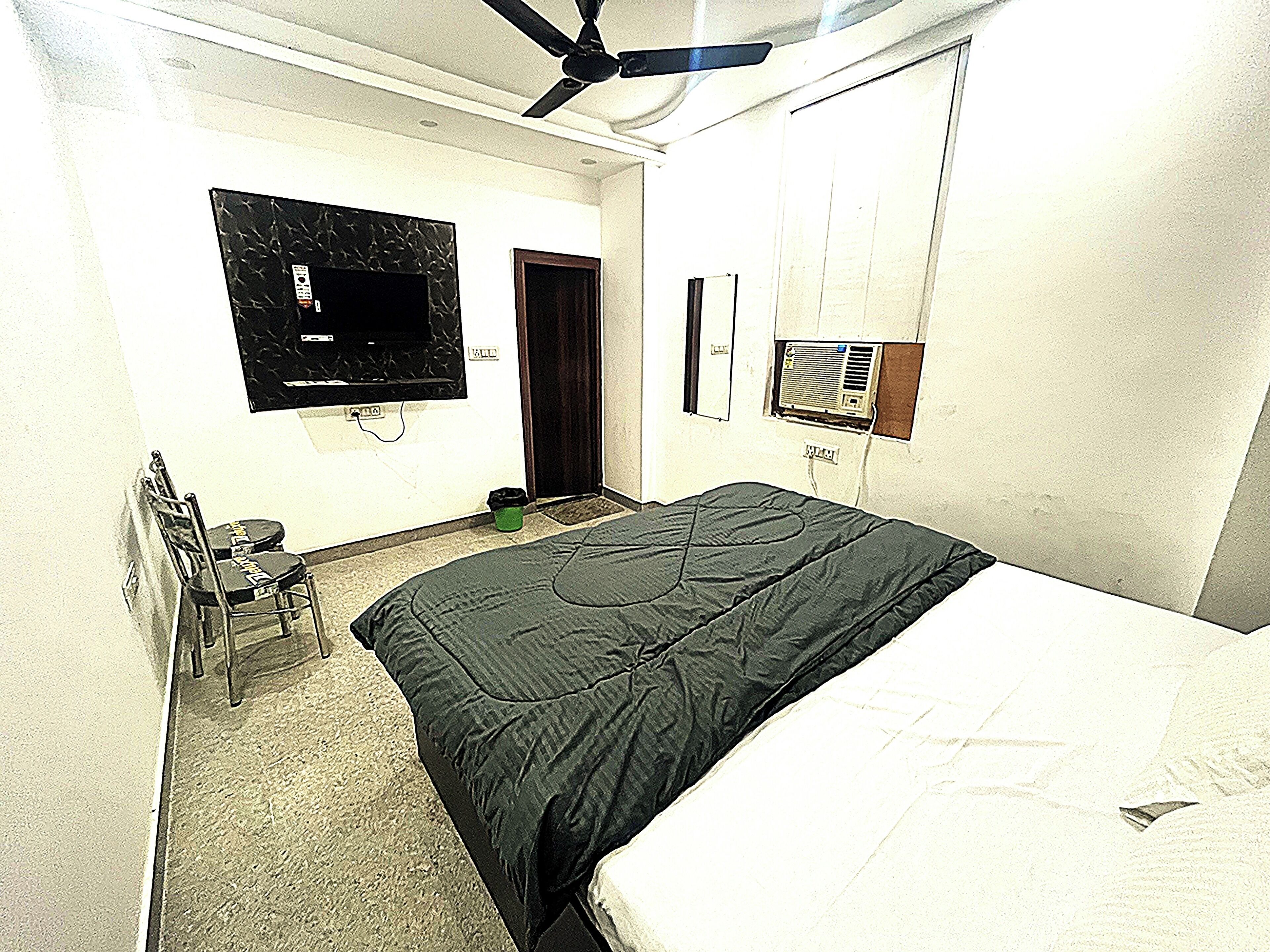 A bedroom with a bed, a ceiling fan, a TV, and a wardrobe.