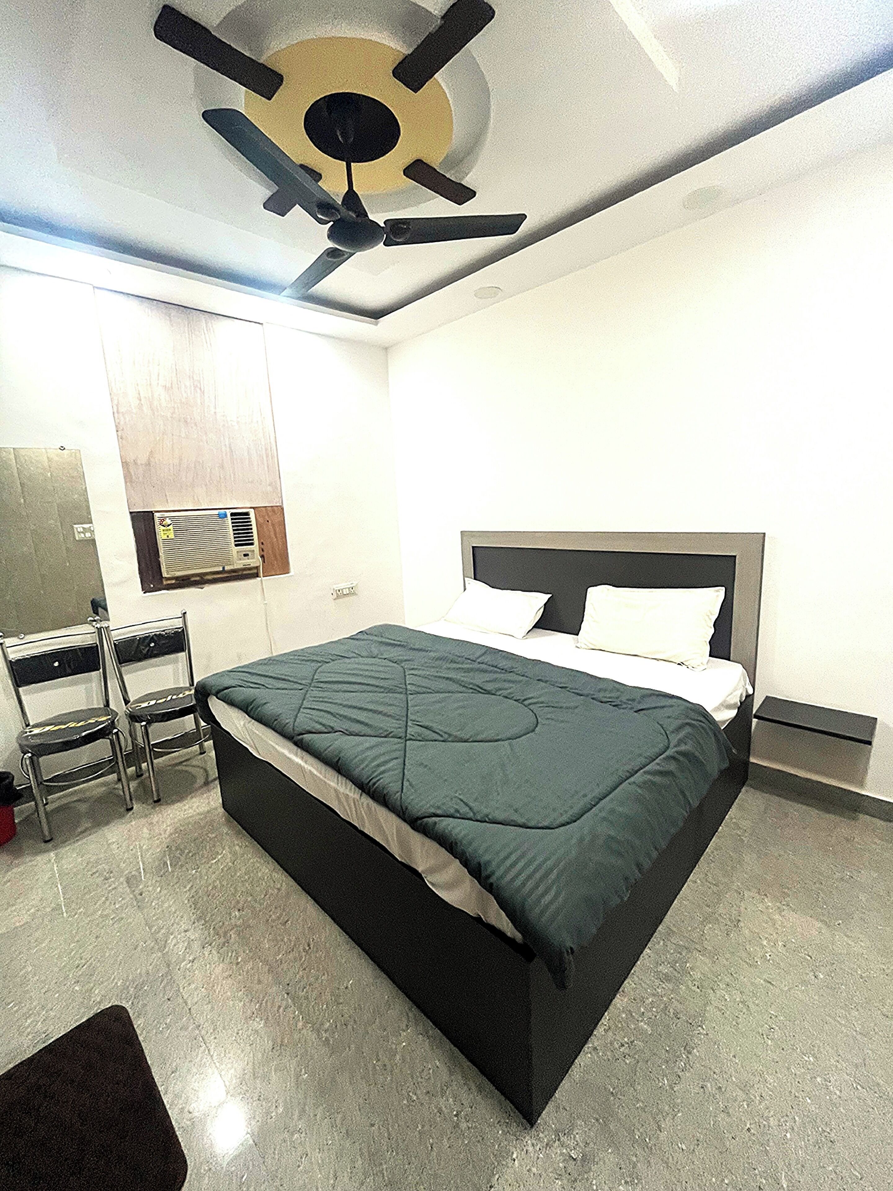 Un dormitorio con cama, una silla, un escritorio y un ventilador de techo.