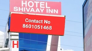 Segnaletica di un hotel con la scritta 'HOTEL SHIVAAY INN' e un numero di telefono '8601051468'.