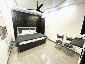 A bedroom with a bed, a desk, and a chair.