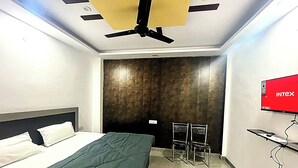 Una camera d'albergo con un letto, una scrivania, una sedia, un televisore e una ventola a soffitto.
