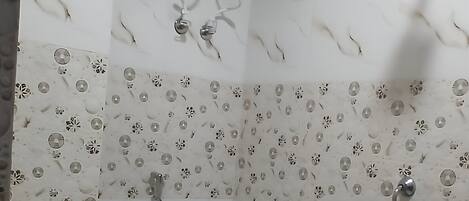 A bathroom with a toilet, a shower, and a wall-mounted air conditioner.