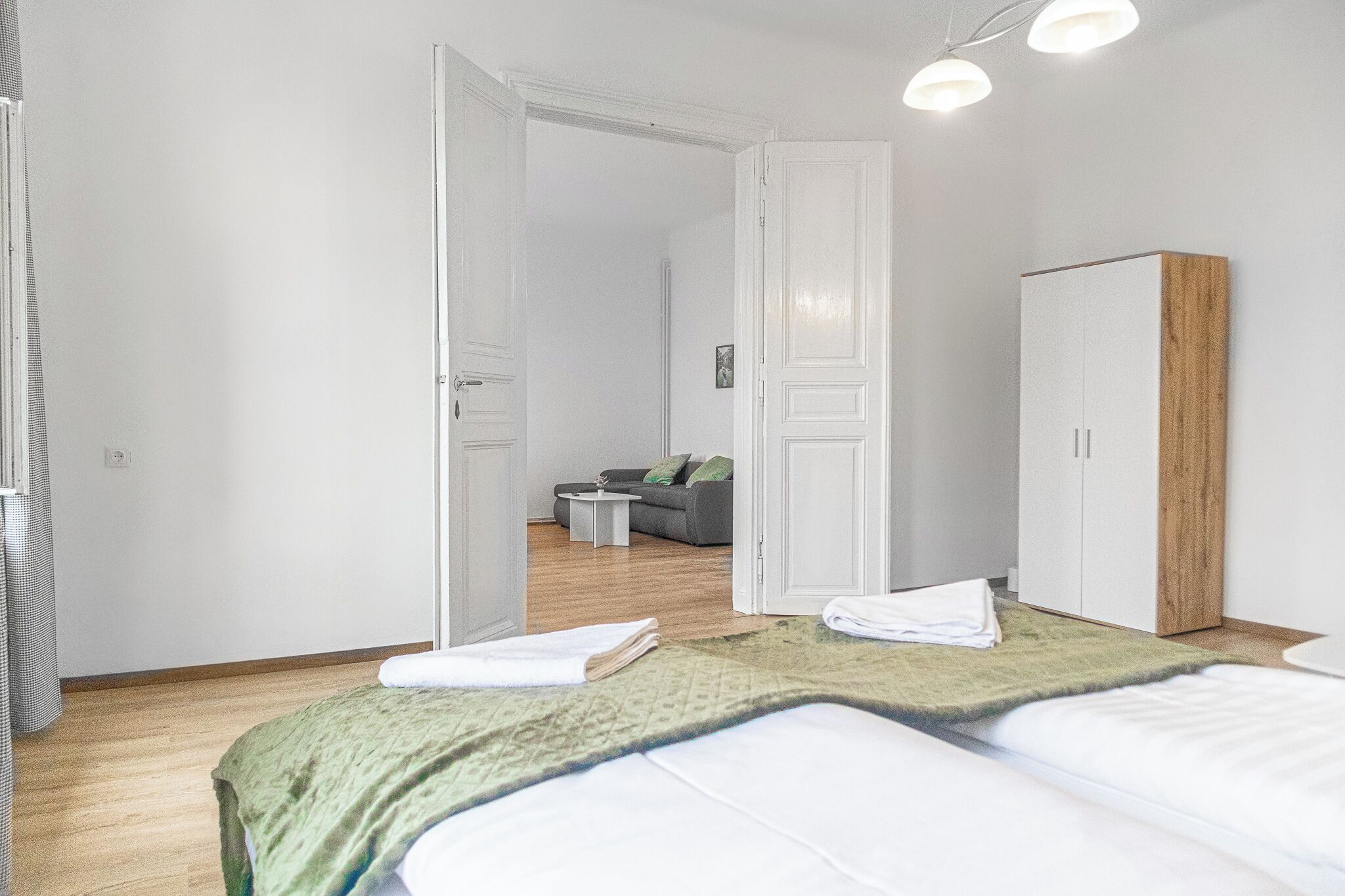 Ein Hotelzimmer mit Bett, Schrank und einer Sitzecke inklusive Sofa und Couchtisch.