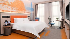 Ett hotellrum med en stor säng, ett skrivbord, en stol och en tv.