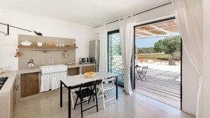 Una cocina moderna con comedor, grandes puertas correderas de vidrio a un patio exterior y vistas del paisaje circundante.