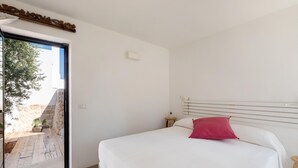 Un dormitorio con cama, mesita de noche, ventana y vistas al exterior.