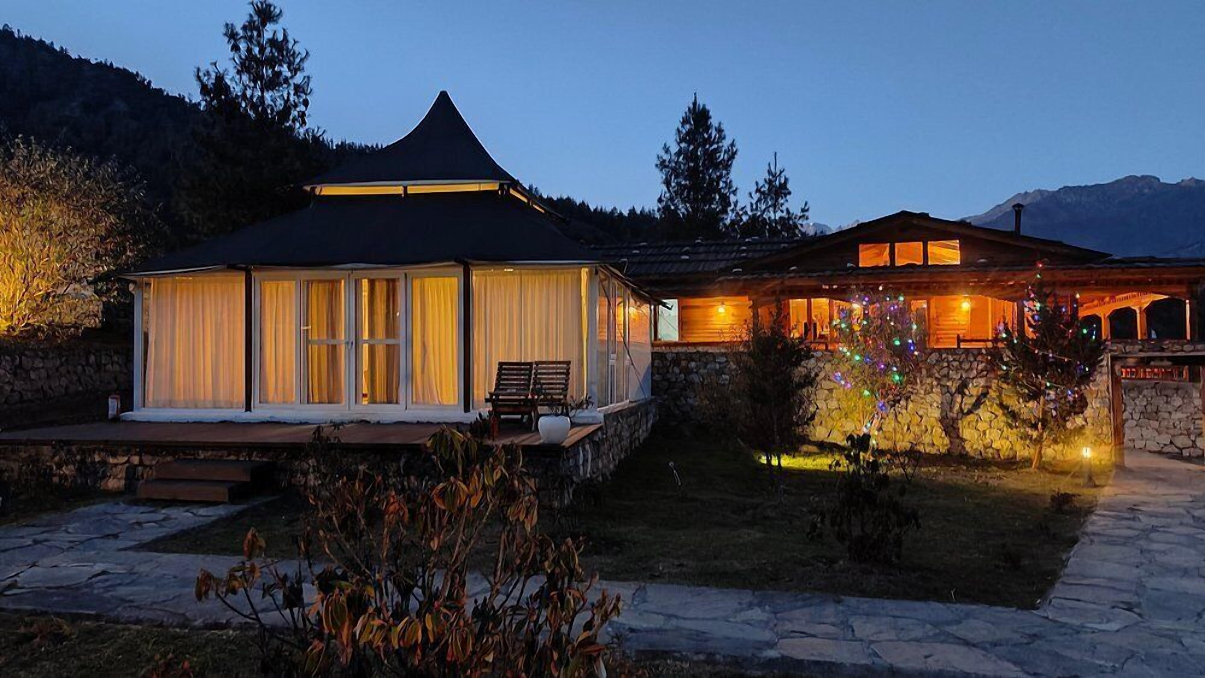 A two-story house with a covered patio and a stone wall.