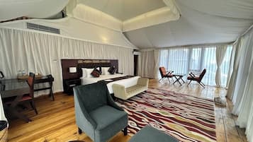A tented room with a bed, a desk, a chair, and a sofa.