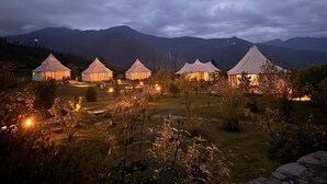 Eine Reihe Zelte vor einer Bergkulisse, umgeben von einem angelegten Garten.