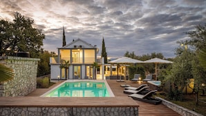 Une maison moderne dotée d’une piscine, d’un espace salon extérieur et d’un mur en pierre.