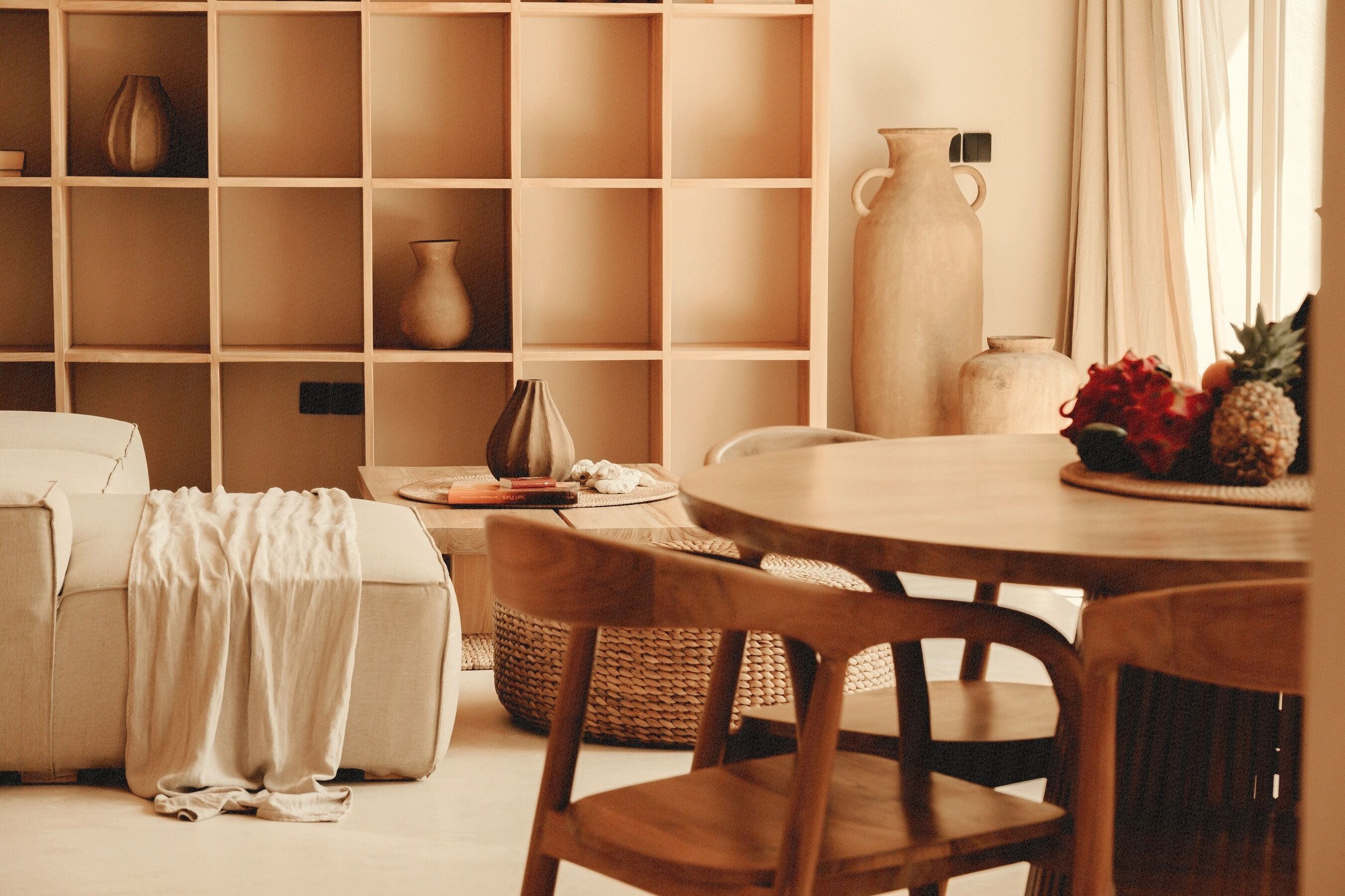 Un accogliente soggiorno con un divano, un tavolino rotondo in legno e una libreria con oggetti decorativi.