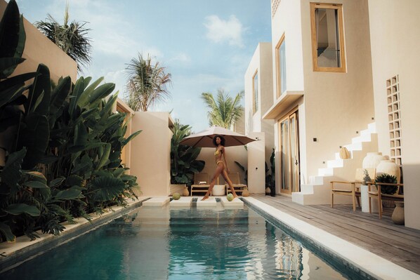 A pool area with a person in a bikini, surrounded by plants and modern architecture. - Nori Boutique Villas (Pecatu)