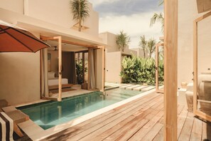 A modern pool area with a wooden deck, a glass-enclosed room, and tropical plants. - Nori Boutique Villas (Pecatu)