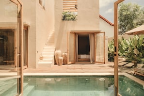 A modern house with a pool, wooden deck, and a staircase leading to a balcony. - Nori Boutique Villas (Pecatu)