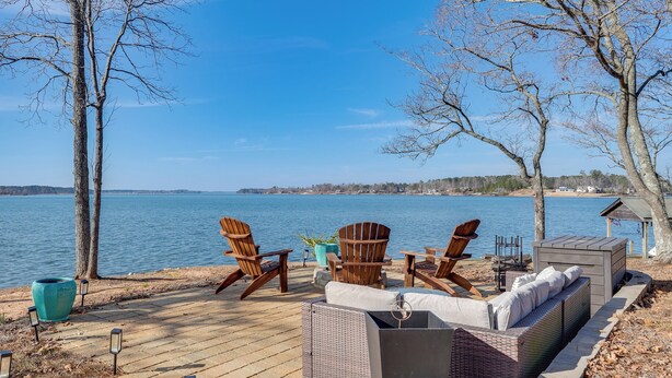 Une terrasse au bord de l’eau avec des sièges extérieurs, un foyer et une vue sur le lac.