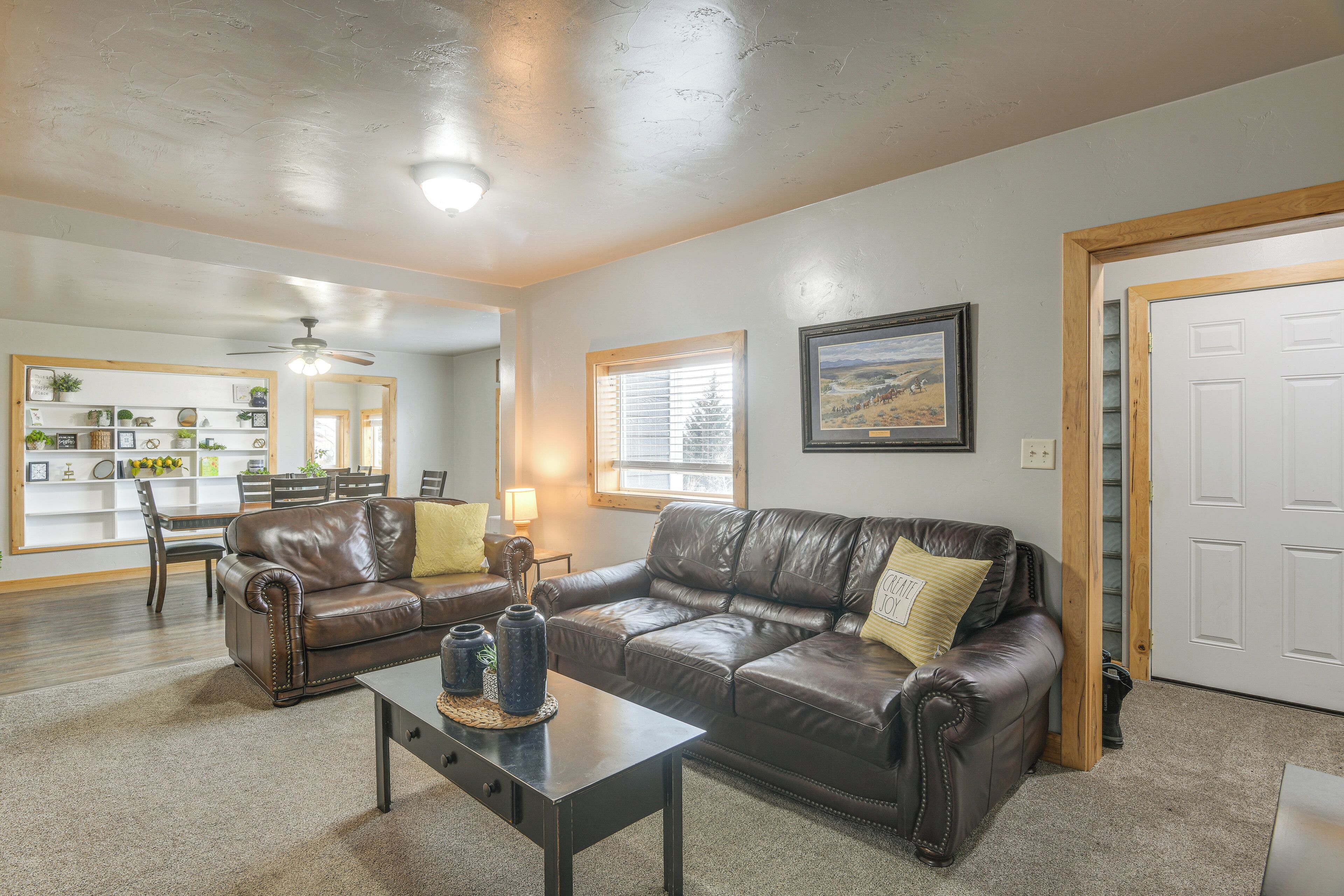 A living room with two leather sofas, a coffee table, and a dining area with a table and chairs.