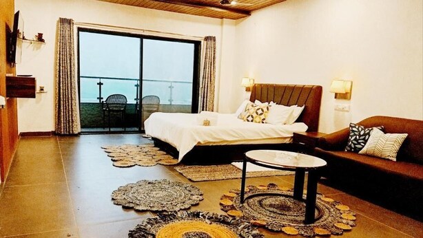 Une chambre avec un lit, un canapé, une table basse et un balcon avec une chaise.