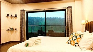 Une chambre d’hôtel avec un grand lit, une vue par une porte coulissante, une chaise et une petite table avec une lampe.