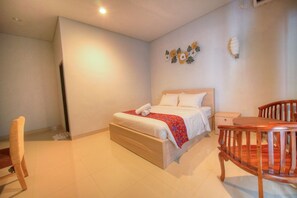 A bedroom with a bed, bedside table, chair, and a wall decoration. - The Joy Rooms Penida (Penida Island)