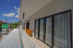 A modern building with a covered outdoor area, a sign for a Merta Mart, and a view of the street. - The Joy Rooms Penida (Penida Island)
