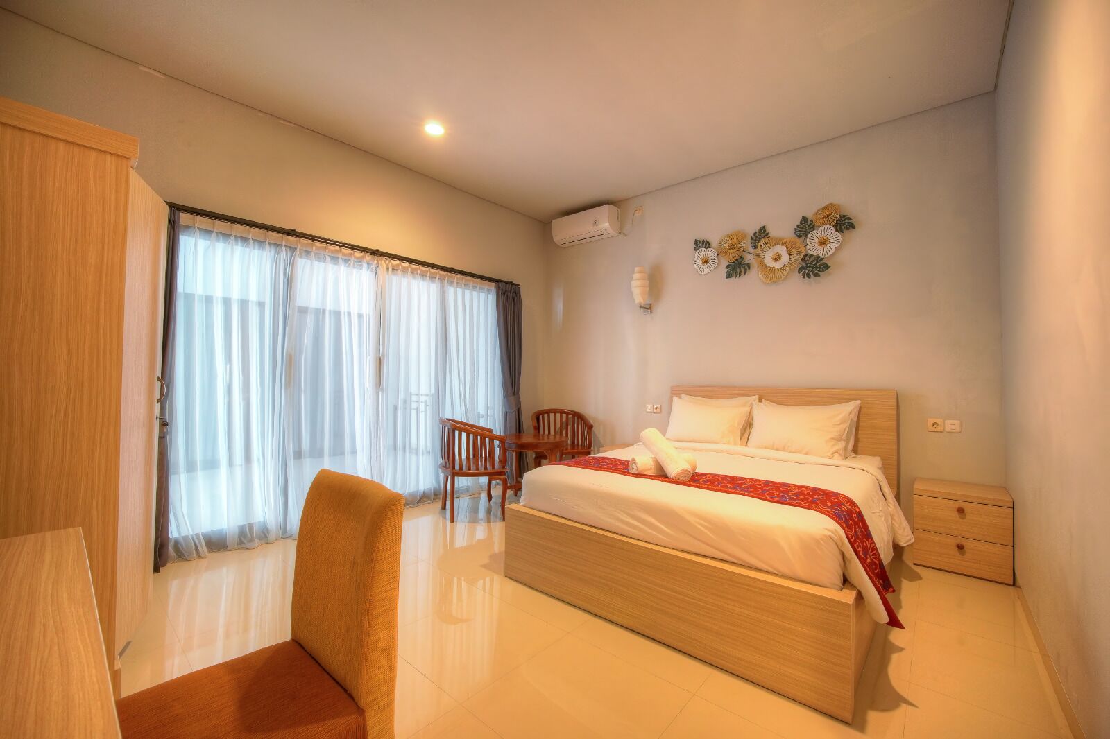 A hotel room with a bed, a chair, a desk, and a window with curtains.